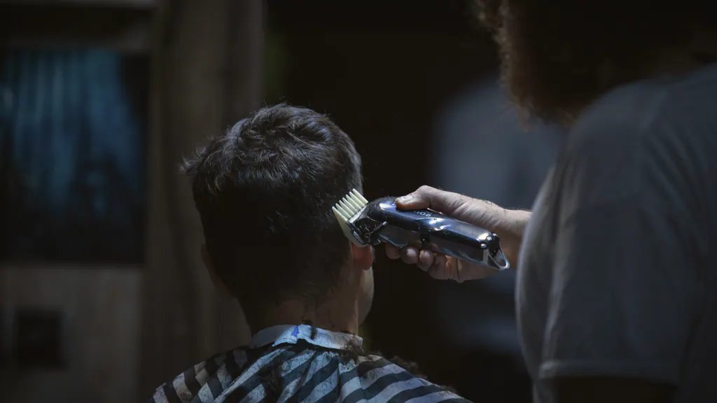 Barber finishing a scissor cut under warm lights in the Halden & Crane shop