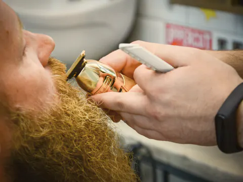 Barber shaping a beard with a trimmer