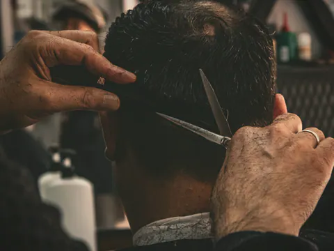 Barber cutting hair with scissors and a comb