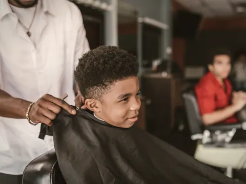 Child having a haircut in a barber chair